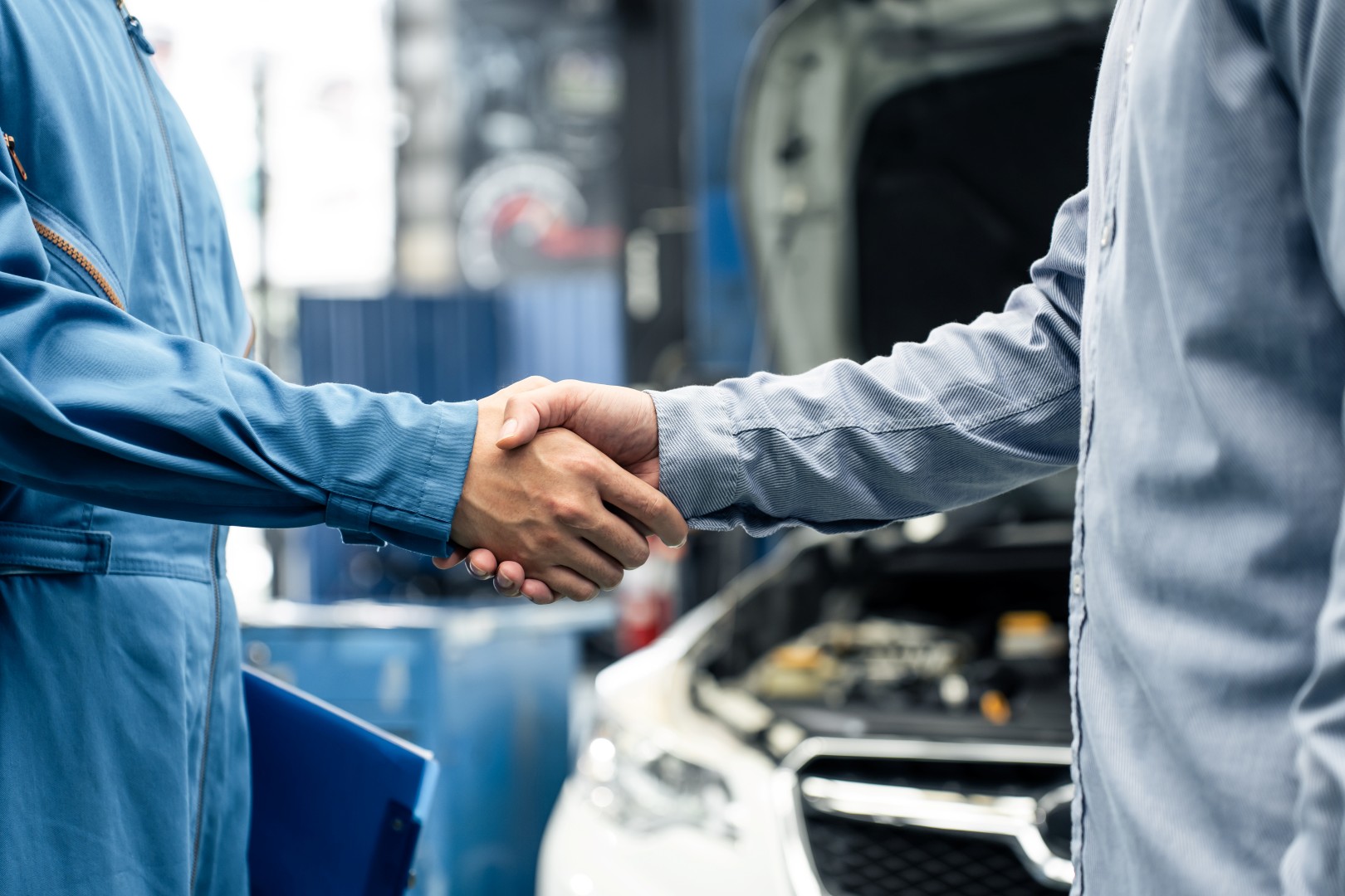 two men shaking hands next to a car